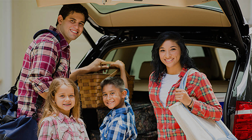 Smiling young family of four at the back of their car - Free Insurance Quotes - Contact Us now